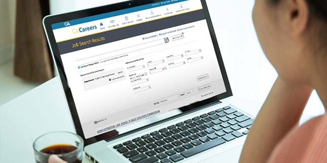 Viewpoint from over a person's shoulder at their laptop screen. The CalCareers webpage is visible on the screen.