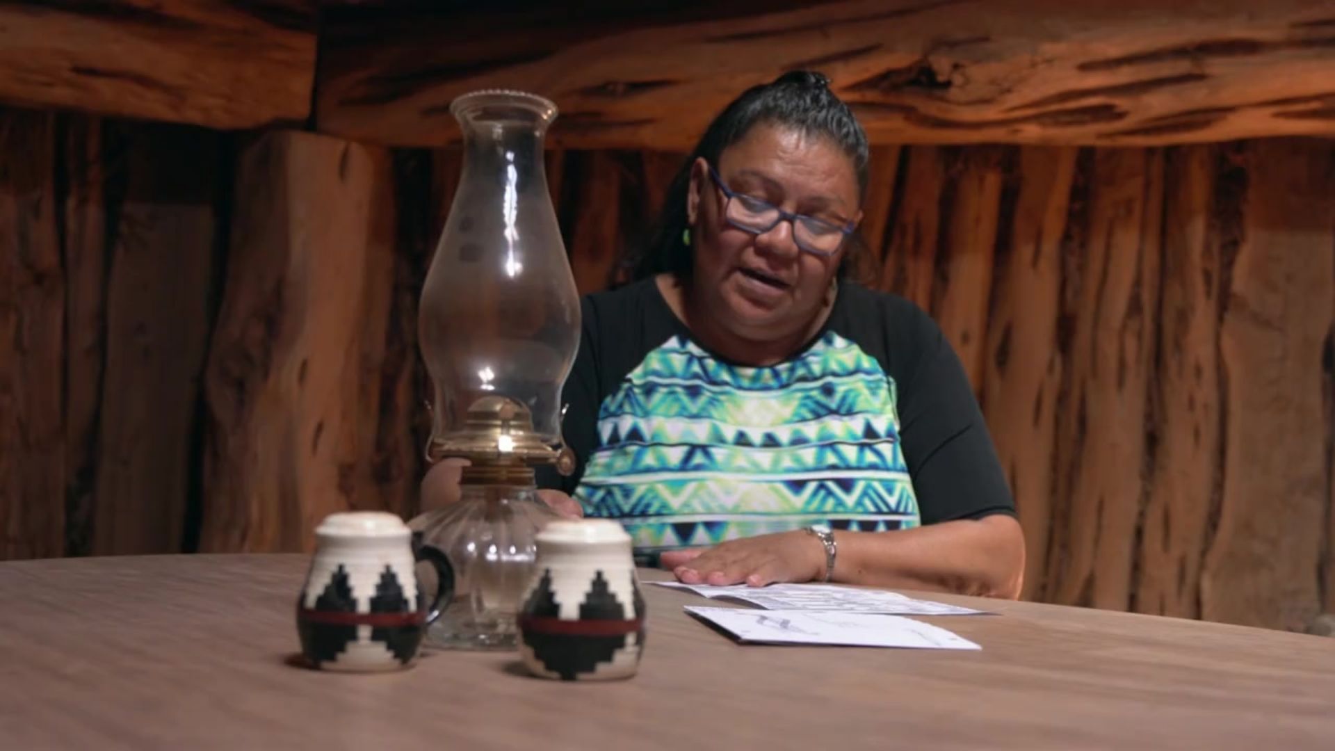 Native American woman at home at a table, looking at paperwork.