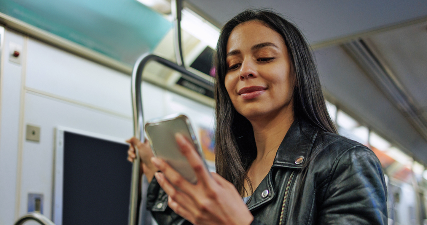 Youn woman on metro, looking at her cell phone